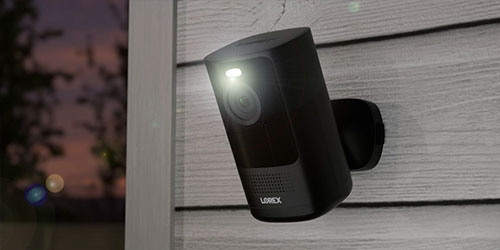 Lorex 4K Spotlight Battery Wi-Fi Security Camera on exterior house side wall with Deterrent Spotlight on